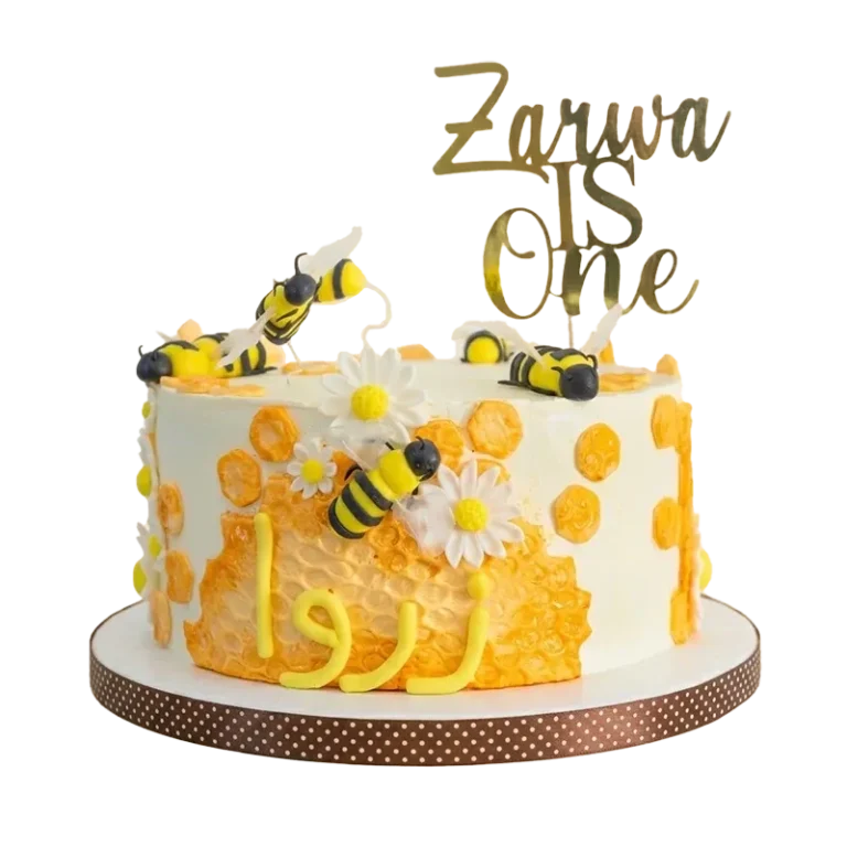 Honeycomb bumblebee first birthday cake with bee figures, daisies, honeycomb pattern, and Zarwa is One topper
