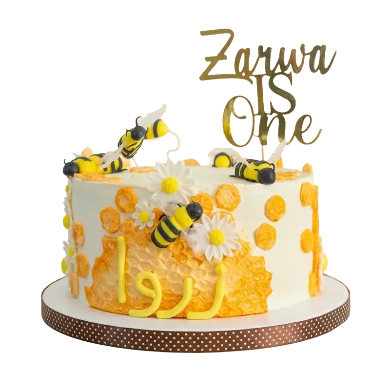 Honeycomb bumblebee first birthday cake with bee figures, daisies, honeycomb pattern, and Zarwa is One topper