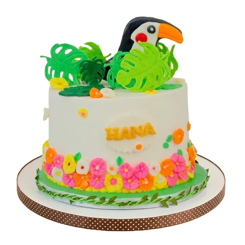 Tropical botanical birthday cake with toucan figure, monstera leaves, tropical flower border, and Hana inscription