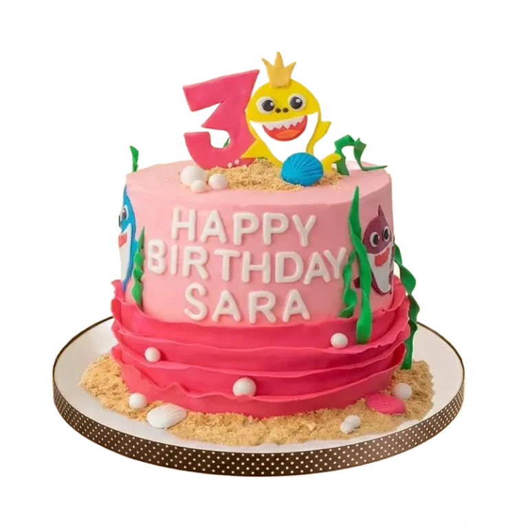 Pink Baby Shark 3rd birthday cake with Baby Shark figure, seaweed, shells, and sand base