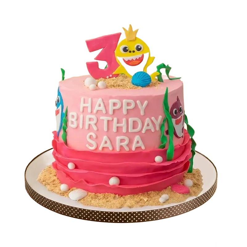 Pink Baby Shark 3rd birthday cake with Baby Shark figure, seaweed, shells, and sand base