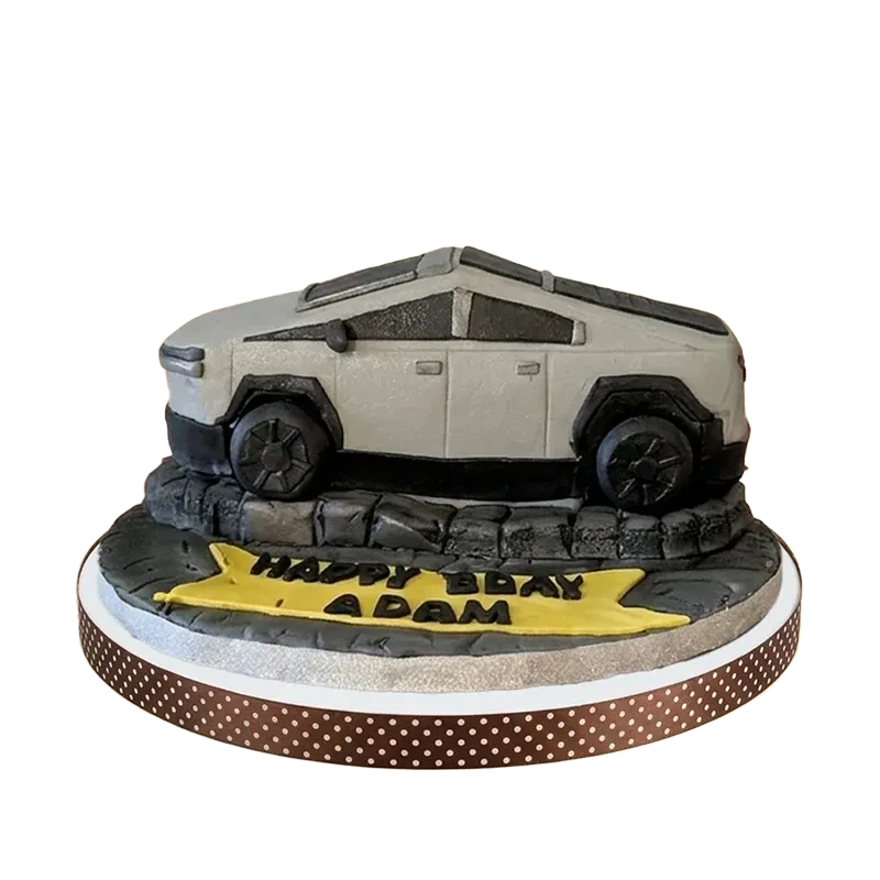 Tesla Cybertruck sculpted birthday cake on rocky terrain base with birthday inscription
