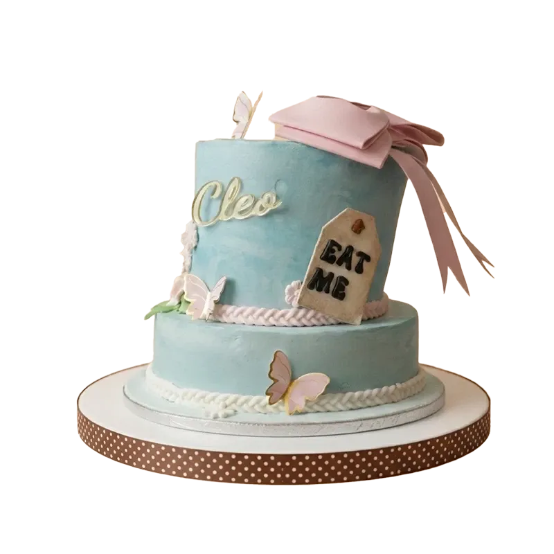 Two-tier Alice in Wonderland birthday cake with pink bow, Eat Me tag, butterflies, and Cleo name inscription