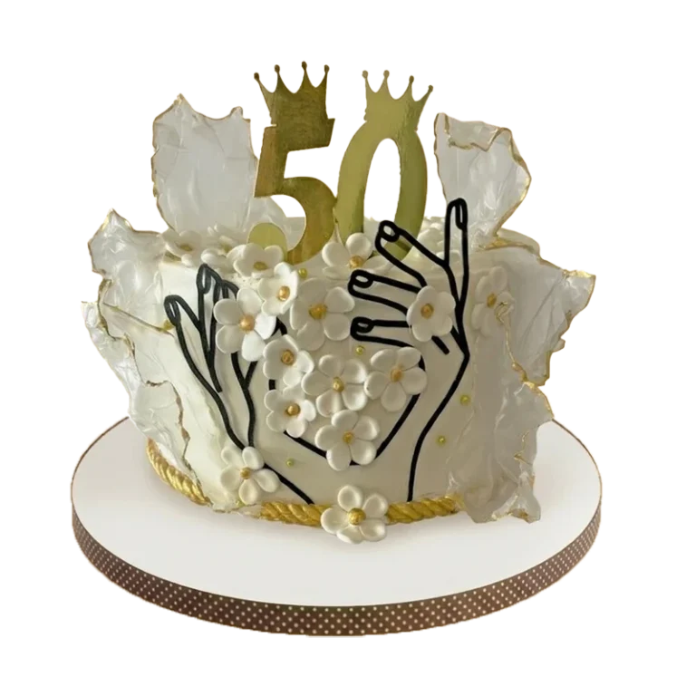 White 50th birthday cake with wafer paper wings, gold number 50, crowns, and hand line art