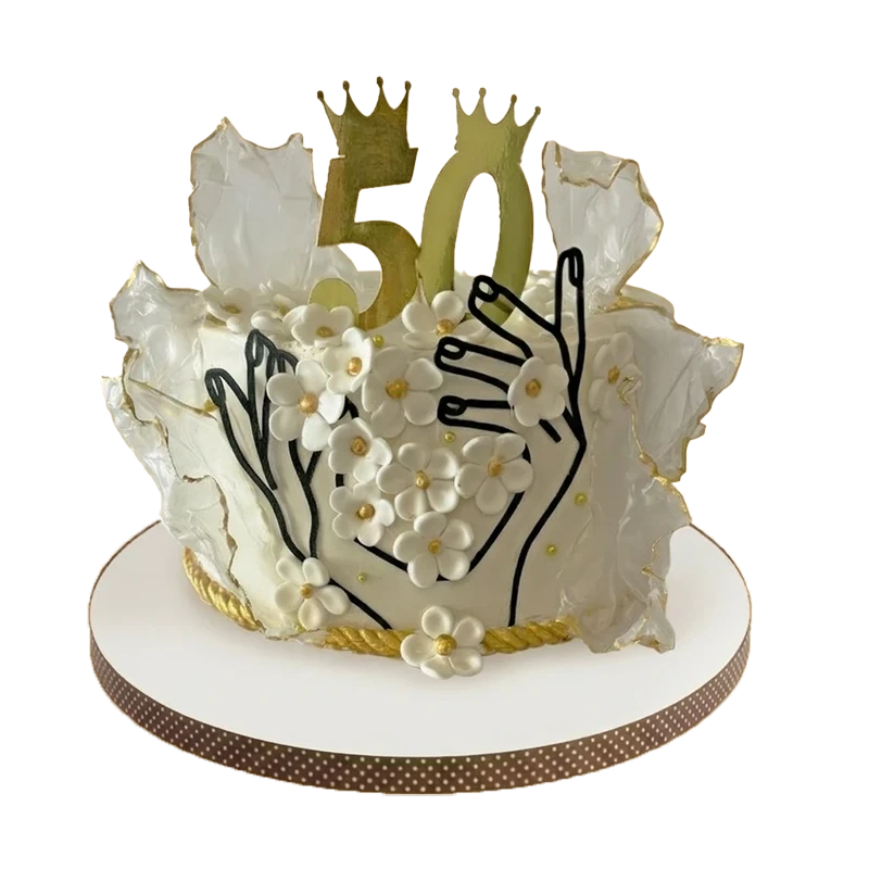 White 50th birthday cake with wafer paper wings, gold number 50, crowns, and hand line art