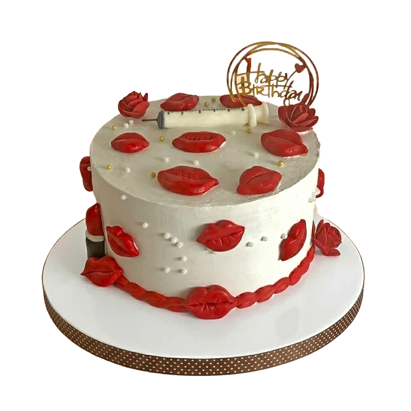 White birthday cake covered with red lips and roses, syringe accent, and gold hoop topper
