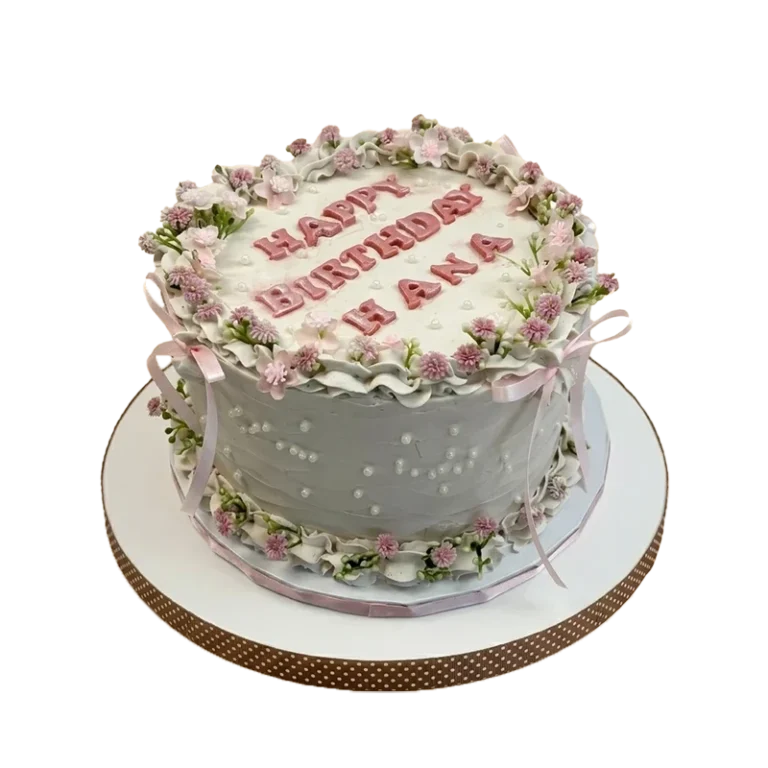 Grey birthday cake with lavender floral wreath crown, pink ribbon bows, and pearl dots