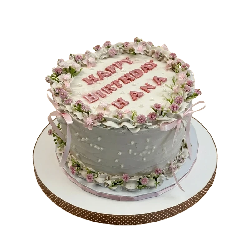 Grey birthday cake with lavender floral wreath crown, pink ribbon bows, and pearl dots