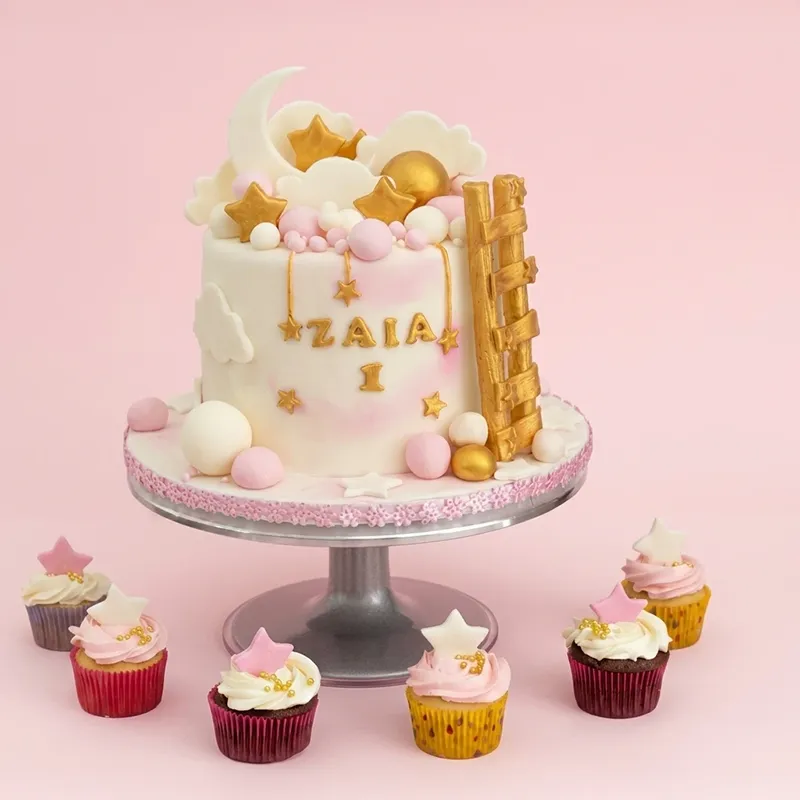 Celestial Dreams first birthday cake with gold stars, moon, ladder, and star-topped cupcakes