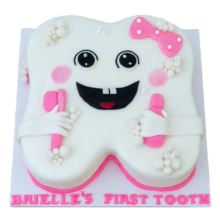 White tooth-shaped first tooth cake with pink bow, smiley face, and pink toothbrushes