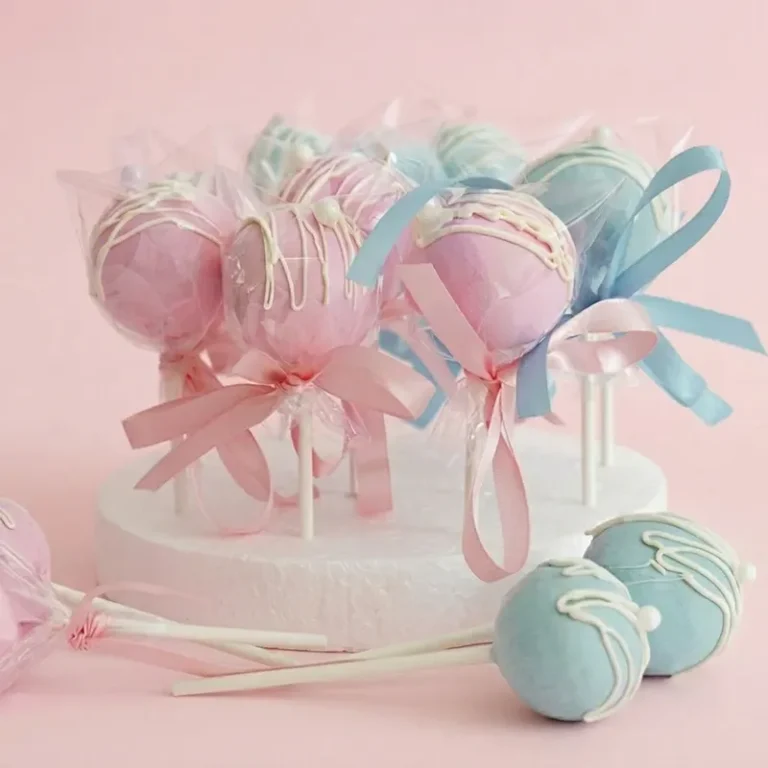 Sweet Suspense gender reveal cake pops in pink and blue with white drizzle and ribbon bows