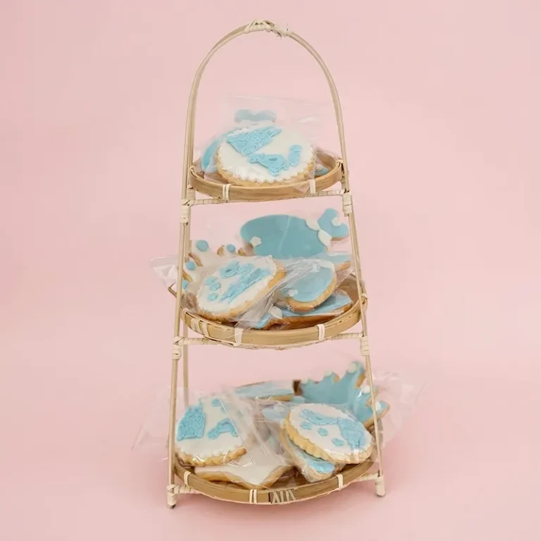 Royal Storybook blue and white crown and whale-themed cookies on a three-tier rattan stand