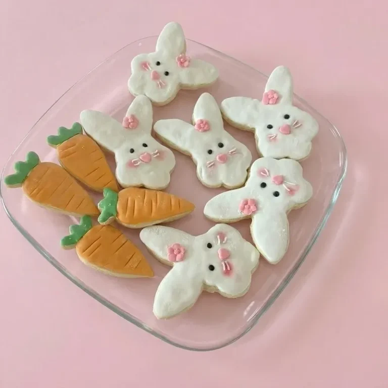 Bunny Patch white bunny-shaped cookies with pink accents and carrot cookies on a glass plate