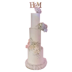 Four-tier ivory wedding cake with cascading pink and lavender flowers and monogram topper