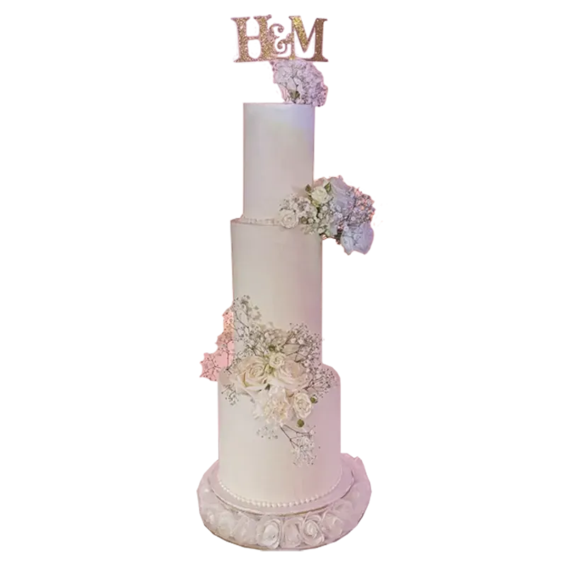 Four-tier ivory wedding cake with cascading pink and lavender flowers and monogram topper