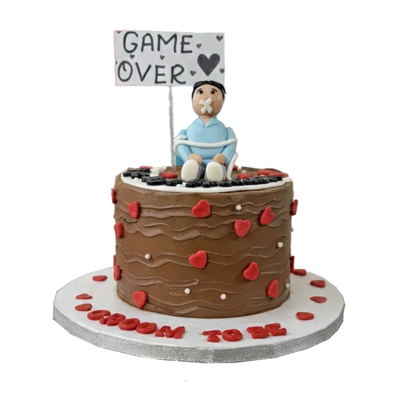 Chocolate bachelor cake with tied groom figure, red hearts, and Game Over sign topper