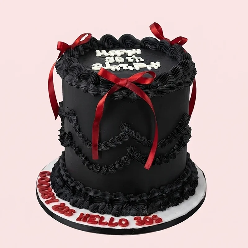 Tall black buttercream birthday cake with red ribbon bows and piped borders by Cakeville Scarborough