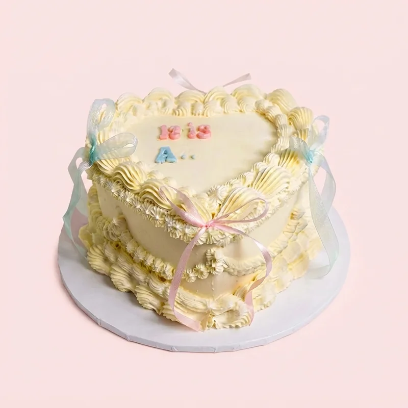 Vintage cream heart shaped gender reveal cake with pink and blue ribbon bows by Cakeville Scarborough