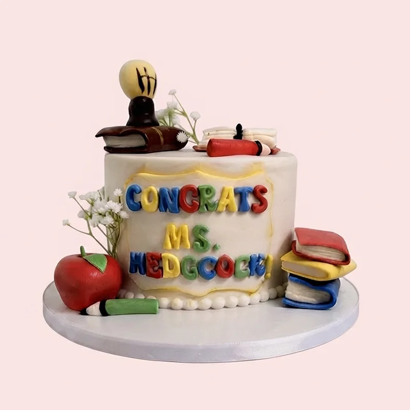White teacher appreciation cake with fondant apple, books and colourful lettering by Cakeville Scarborough