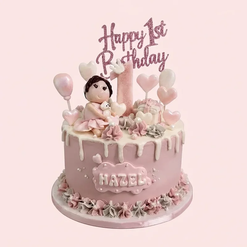 Pink first birthday cake with fondant baby girl figure, hearts and white drip by Cakeville Scarborough
