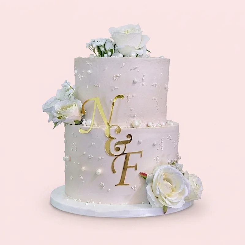 Two-tier white wedding cake with sugar pearls, white roses and gold monogram by Cakeville Scarborough